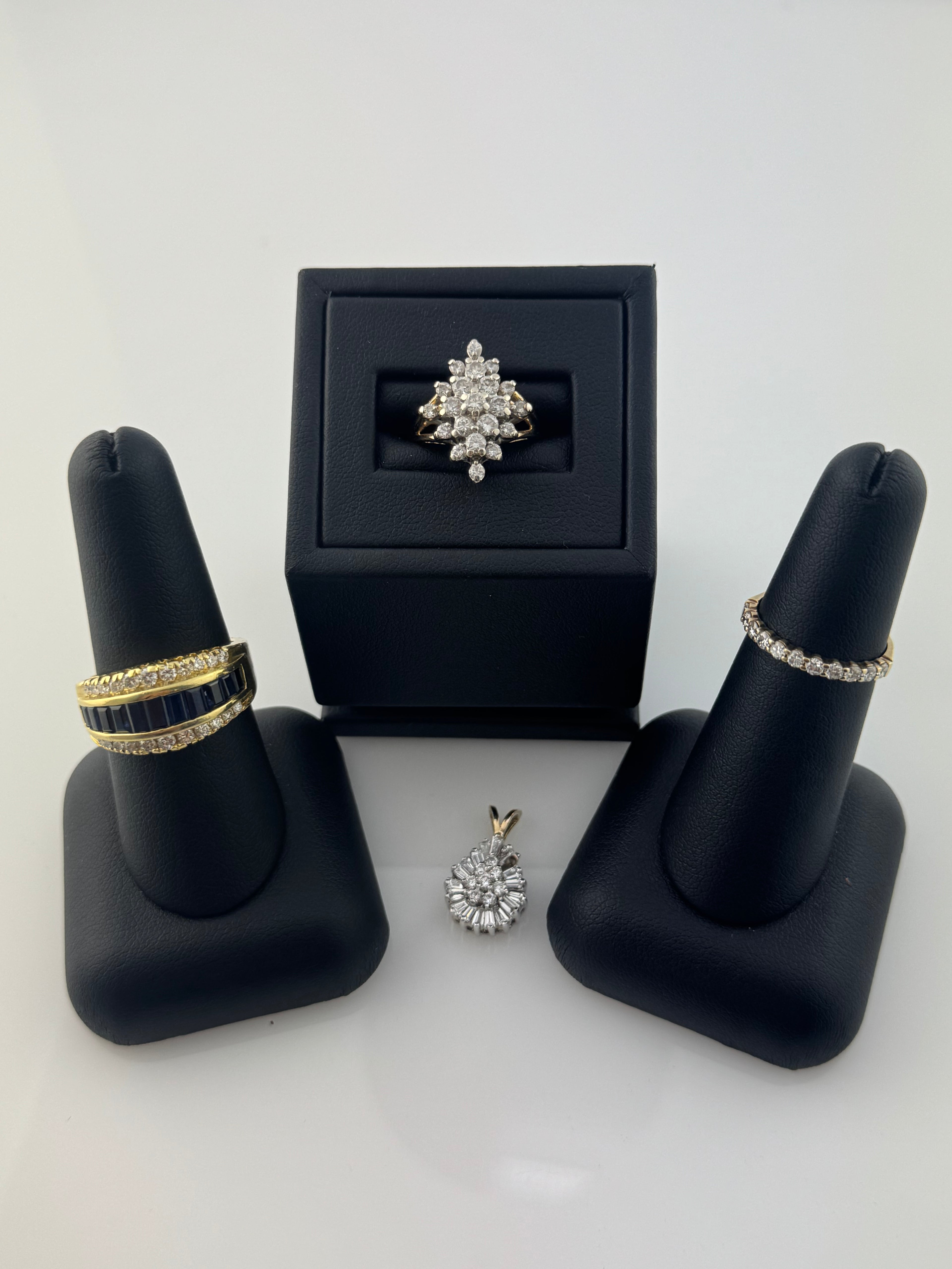 Jewelry set including rings and earrings on black stands with a white background
